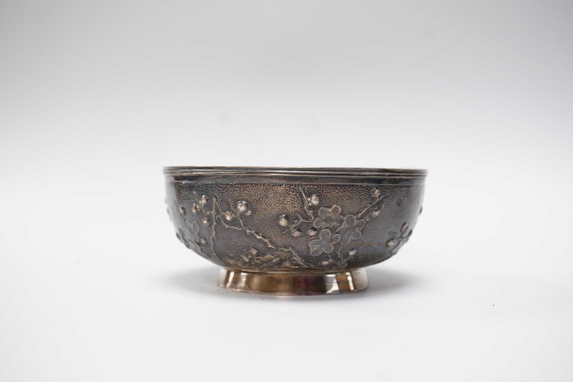 A late 19th/early 20th century Chinese Export white metal bowl, by Wang Hing, Hong Kong, embossed with blossoming prunus branches, diameter 10.6cm, 113 grams.